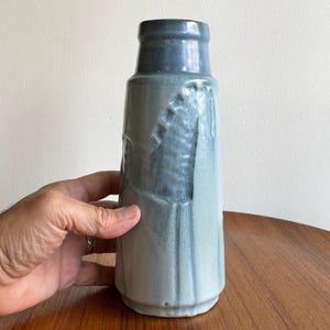 Puede incluir: Un jarrón de cerámica azul y blanco con un diseño texturizado. El jarrón tiene un cuello estrecho y una base ancha.