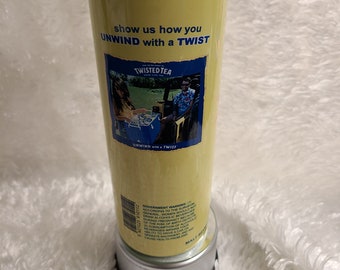 May include: A yellow and blue can of Twisted Tea Hard Iced Tea with the text "show us how you UNWIND with a TWIST" and "5% ALC./VOL." printed on the can. The can is sitting on a silver base.
