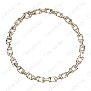 May include: A gold-toned metal chain necklace arranged in a circular shape. The necklace consists of repeating T-shaped links connected by small rectangular bars, creating a uniform, geometric pattern throughout the entire length of the jewelry piece.