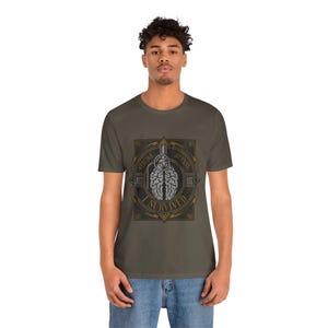May include: Olive green t-shirt with a graphic of a brain inside a grenade, and the words "Stroke, Just Use, Defeat, I Survived" in a circular pattern. The design is in grey and gold.