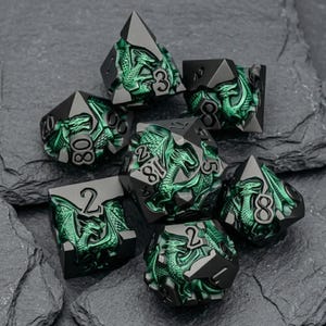 May include: A set of seven polyhedral dice featuring a matte black finish with intricate, raised metallic green dragon motifs on each face. The numbers are clearly engraved in a bold, black font, contrasting against the vibrant green dragon artwork.