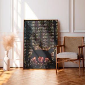 Op de afbeelding: Een ingelijste kunstdruk met een zwart silhouet van een kat tegen een achtergrond van kleurrijke computercode. Het kunstwerk wordt tentoongesteld in een kamer met een houten stoel en een vaas met gedroogde bloemen.