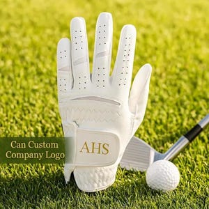 May include: A white golf glove with the initials "AHS" in gold lettering is displayed on green grass. The glove has small ventilation holes and is next to a golf ball and club. Text on the image reads "Can Custom Company Logo."
