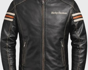 Puede incluir: Una chaqueta de cuero negra para motocicleta con cuello alto, cremallera frontal completa y dos bolsillos con cremallera en la cintura. Las mangas muestran rayas horizontales naranjas y crema, y el texto Harley-Davidson está impreso en blanco.