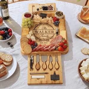 May include: A bamboo charcuterie board with a variety of cheeses, crackers, fruits, and meats. The board is engraved with "The Walker Family" and "EST. 2025". Includes a set of cheese knives and a corkscrew. A perfect gift for a housewarming.