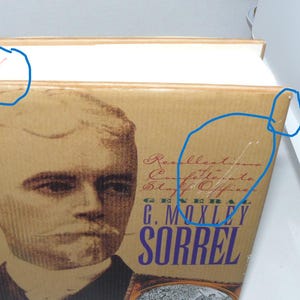 May include: A hardcover book with a tan dust jacket featuring a portrait of a man with a mustache. The text reads Recollections of a Confederate Staff Officer and G. Moxley Sorrel. There is a small red X mark on the top edge and minor wear.
