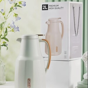 May include: A white 2L thermos flask with a wooden handle and a matching lid. The flask is next to its packaging, which reads "PREMIUM HIGH QUALITY". The flask has a gold-coloured accent on the lid.
