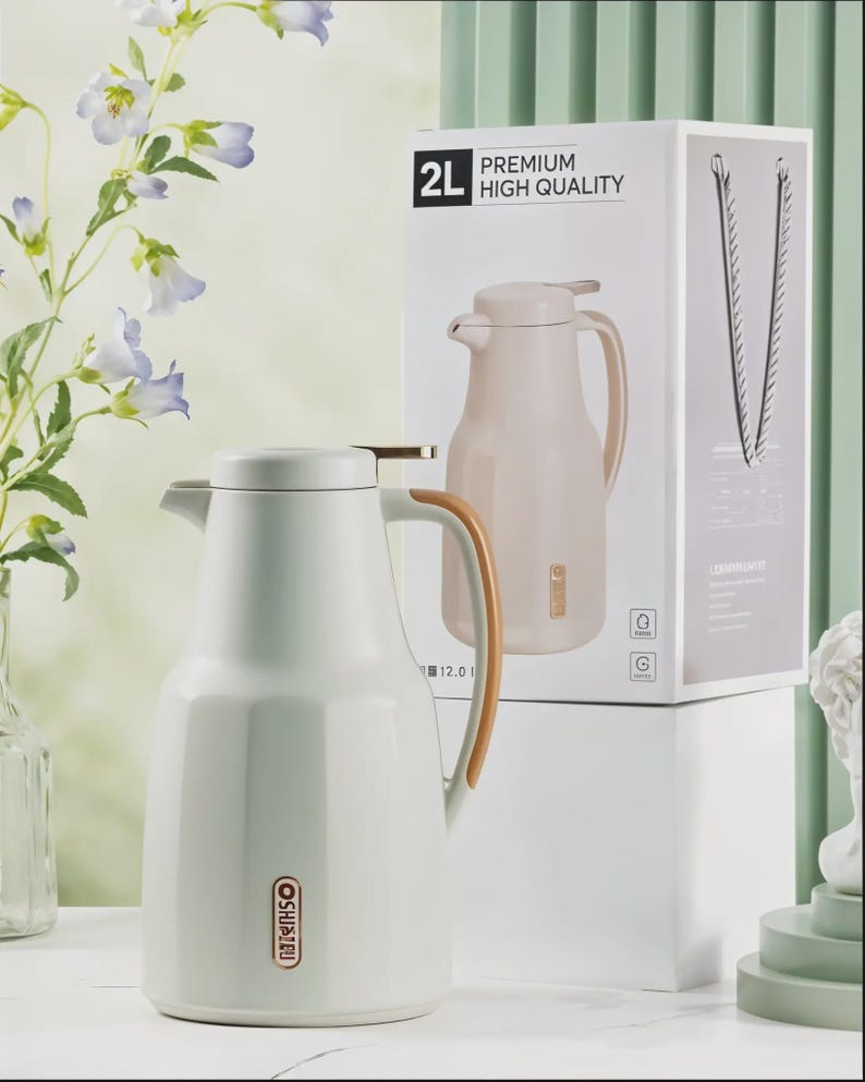 May include: A white 2L thermos flask with a wooden handle and a matching lid. The flask is next to its packaging, which reads "PREMIUM HIGH QUALITY". The flask has a gold-coloured accent on the lid.
