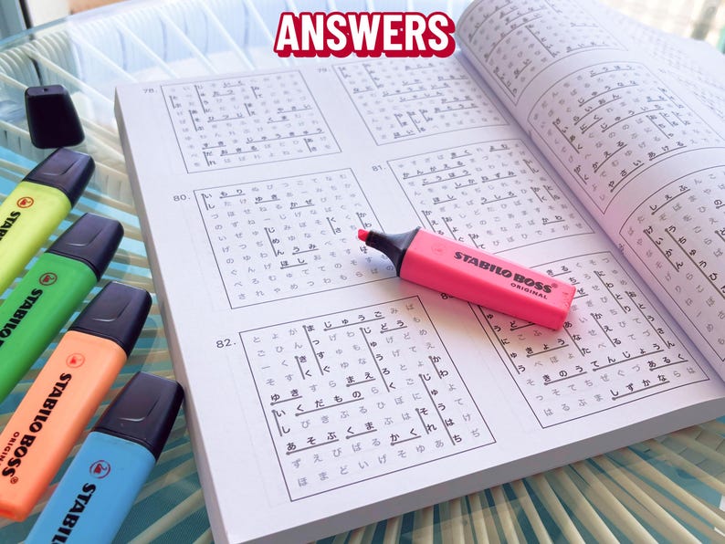 K&ouml;nnte beinhalten: Ein offenes Buch mit japanischen Schriftzeichen und ein pinkfarbener Stabilo Boss Textmarker. Das Wort "ANSWERS" steht oben. Mehrere weitere Textmarker in Gelb, Gr&uuml;n, Orange und Blau sind sichtbar.