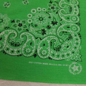 Puede incluir: Pañuelo verde brillante con un diseño de cachemira blanco y negro. La tela es 100% algodón, con un diseño de cachemira clásico y detalles florales. El texto "100% Cotton Made in U.S.A." está impreso en la tela.