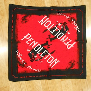 Pode incluir: Bandana quadrada vermelha e preta com as palavras "PENDLETON WHISKY" em branco, uma silhueta de cavalo a empinar e a frase "Let'er Buck". O texto "TRUE WESTERN TRADITION" também está presente.