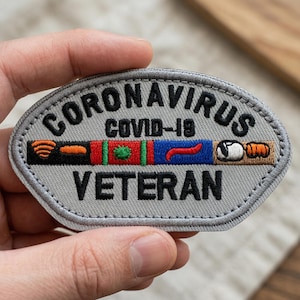May include: Embroidered patch with the words "CORONAVIRUS" and "VETERAN" in black on a gray oval. The patch features a colorful design with orange, red, green, blue, and white elements, and the text "COVID-19".