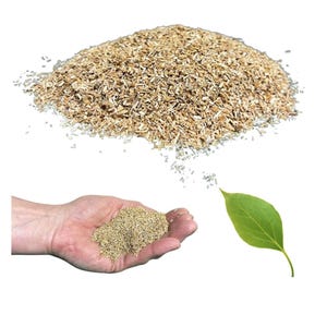 Puede incluir: Un montón de virutas de madera de color marrón claro y un puñado en una mano. Una hoja verde está a la derecha. Las virutas de madera son probablemente para jardinería o paisajismo.
