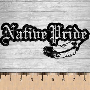 May include: Black and white Native Pride design featuring stylized text and a feather illustration. The design is set against a light gray wood grain background, with a ruler at the bottom. The text is in a gothic font.