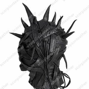 Op de afbeelding: Zwart leren masker met meerdere puntige spikes en verweven leren stroken. Het masker heeft een rits aan de achterkant en is ontworpen om het hele hoofd te bedekken. De tekst "scorpionleather" herhaalt zich.