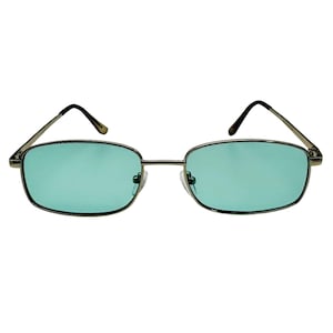 May include: Rectangular-framed sunglasses with a silver metal frame and teal-colored lenses. The glasses have a classic, retro design, suitable for various styles. The lenses are a solid, opaque color, offering a unique aesthetic.