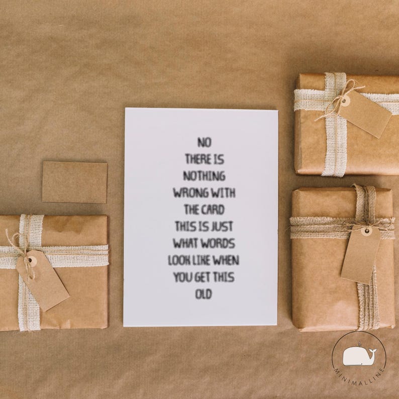Peut inclure: Une carte blanche avec du texte noir qui dit "NO THERE IS NOTHING WRONG WITH THE CARD THIS IS JUST WHAT WORDS LOOK LIKE WHEN YOU GET THIS OLD" est entour&eacute;e de cadeaux emball&eacute;s et d'une petite carte.