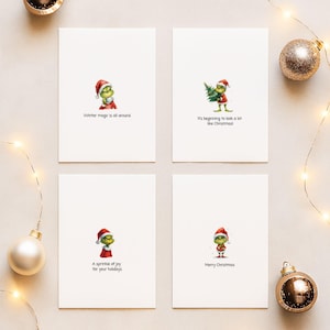 Peut inclure: Quatre cartes de vœux de Noël blanches avec des illustrations du Grinch. Chaque carte présente un design différent du Grinch et un message de vacances : "Winter magic is all around", "It's beginning to look a lot like Christmas!", "A sprinkle of joy for your holidays" et "Merry Christmas."