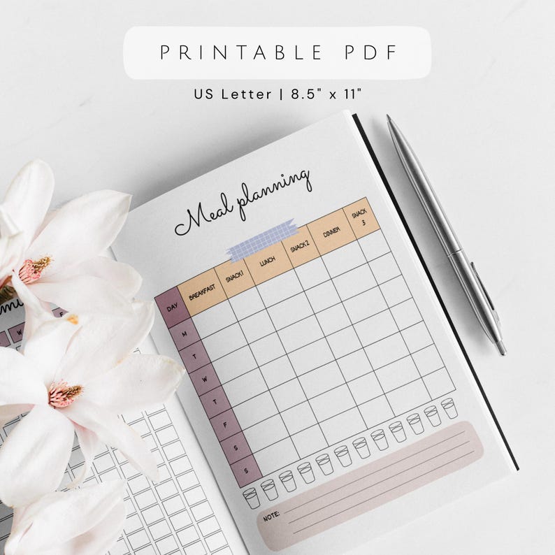 May include: A printable PDF meal planning journal, US Letter size 8.5" x 11". The open journal displays a weekly meal planning grid with sections for breakfast, lunch, snacks, and dinner. A silver pen rests on the page. The words "Meal planning" are written in cursive.
