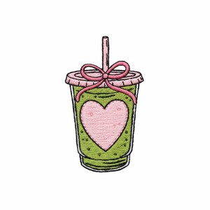 May include: An embroidered patch of a green smoothie or beverage in a clear plastic cup with a lid. The cup features a large pink heart in the center and a pink bow tied around the straw and lid. The design has black outlines and stitching.