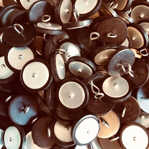 Peut inclure: Un tas de boutons noirs et blancs avec une boucle argentée sur le dessus. Les boutons ont une finition lisse et brillante.