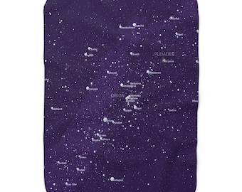 Puede incluir: Una manta rectangular de felpa con un fondo morado oscuro salpicado de puntos blancos, que simulan estrellas. La manta muestra las constelaciones de Orión y las Pléyades, con nombres de estrellas en texto blanco. Decoración celestial.