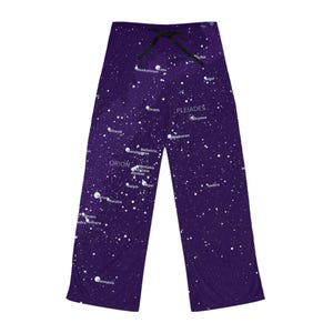 May include: Purple pajama trousers with a celestial design. The trousers feature a constellation pattern with white stars and the names of constellations like Orion and Pleiades. They have a black drawstring at the waist.