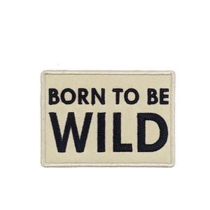 May include: A rectangular patch with the text "BORN TO BE WILD" in black letters on a beige background. The patch has a stitched border.
