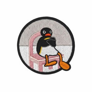 May include: Embroidered patch featuring a cartoon penguin sitting on a pink chair. The penguin is black and white with an orange beak and feet. The patch is circular with a black border and a gray background.