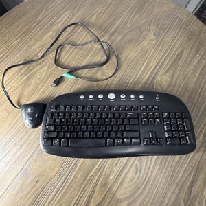 May include: A black Logitech computer keyboard with a curved design and a separate black receiver unit connected by a long black cord. The keyboard features a standard QWERTY layout, a numeric keypad, and several circular media control buttons.