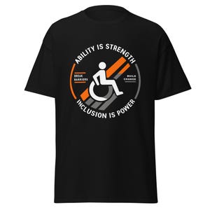 May include: Black t-shirt with a circular graphic featuring a wheelchair user icon. The text reads "Ability is Strength" and "Inclusion is Power." Additional text includes "Break Barriers" and "Build Change."