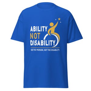 May include: Royal blue t-shirt with the words "ABILITY NOT DISABILITY" in white and yellow. A yellow figure in a wheelchair reaches for a gold star. The text "SEE THE PERSON, NOT THE DISABILITY" is below the main text.