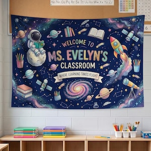 May include: A dark blue space-themed classroom banner featuring an astronaut on the moon, planets, a rocket, a telescope, and books. The text reads: WELCOME TO MS. EVELYN'S CLASSROOM WHERE LEARNING TAKES FLIGHT. The design includes colorful nebulae.
