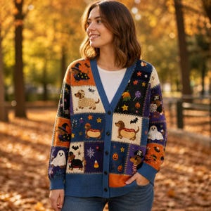 May include: A long-sleeve button-down cardigan featuring a patchwork design with Halloween-themed illustrations of dachshunds in costumes, ghosts, pumpkins, bats, and stars in shades of blue, orange, black, and white over a white shirt.