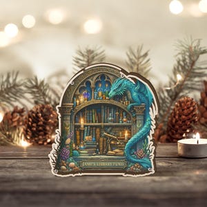May include: A wooden decorative piece featuring a fantasy library scene with a teal dragon. The library is filled with books, candles, and scientific instruments. The text "Jame's Library Fund" is at the bottom.