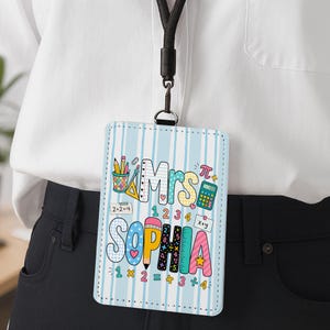 Peut inclure: Un porte-badge rectangulaire vertical avec un fond à rayures bleu clair et blanc. Le motif présente le texte Mrs. SOPHIA entouré d'illustrations scolaires colorées, notamment un crayon, une calculatrice et des équations mathématiques.