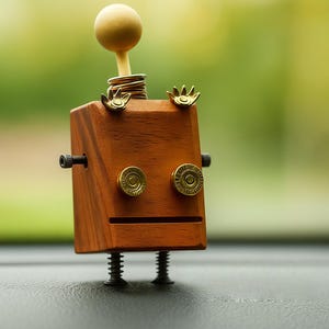 May include: A handcrafted wooden robot with a square body, brass accents, and a ball-shaped head. The robot has screw legs and a spring neck. The eyes are made from brass bullet casings. The robot is a unique decorative item.