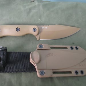 May include: A tan BK-18 knife with a matching sheath and black strap. The knife has a tan handle with three hex screws and a tan blade. The sheath has the KA-BAR logo and a black strap with a snap.
