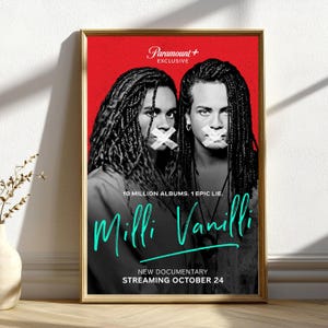 May include: A framed poster with a red background features two people with tape over their mouths. The poster promotes the "Milli Vanilli" documentary, with the text "10 MILLION ALBUMS. 1 EPIC LIE." and "STREAMING OCTOBER 24."
