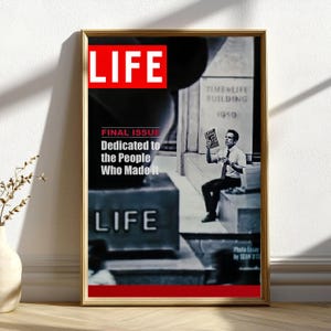 Könnte beinhalten: Ein gerahmter Druck eines LIFE-Magazin-Covers. Der obere Teil des Covers zeigt das Wort "LIFE" in weißen Buchstaben auf rotem Hintergrund. Das Bild zeigt einen Mann, der ein Magazin hält. Der Text lautet "FINAL ISSUE Dedicated to the People Who Made It."