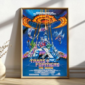 Può includere: Un poster cinematografico incorniciato per "The Transformers: The Movie" con una cornice dorata. Il poster presenta una vivace illustrazione di robot trasformabili in azione su uno sfondo cosmico blu e arancione. Il testo include "Beyond good. Beyond evil. Beyond your wildest imagination."