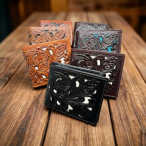 May include: A collection of leather wallets in various colors, including brown, black, and tan. Each wallet features a detailed floral embossed design. The wallets are arranged on a wooden surface.