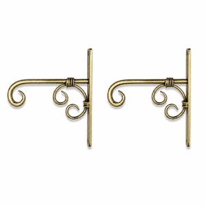 May include: A pair of antique brass-colored metal wall brackets featuring a vertical mounting plate, a horizontal arm with a curved end, and decorative scrollwork supports. Each bracket has two screw holes on the flat vertical mounting bar.