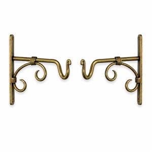 May include: A pair of wall-mounted metal brackets in an antique brass finish. Each bracket features a vertical mounting plate with two screw holes, a horizontal support arm, and a decorative scrollwork design with a curved hook at the end.