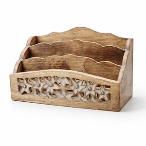 May include: A wooden desk organiser with three compartments. The organiser is light brown with a carved floral design along the bottom. The top edge has a scalloped design.