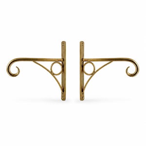 May include: A pair of gold-toned metal wall brackets featuring a vertical mounting plate, a horizontal arm with a curled end, and a diagonal support brace accented with a circular ring detail. The hardware has a smooth, metallic finish.