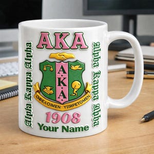 Puede incluir: Taza de cerámica blanca con el escudo de la hermandad Alpha Kappa Alpha en verde y rosa. La taza incluye las letras "AKA" y las palabras "Alpha Kappa Alpha" en verde. También se muestra el año "1908" y el texto "Your Name".