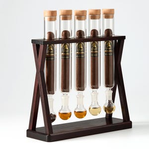 May include: A dark wood stand holding five vertical glass tubes, each containing a brown cigar with a black and gold Davidoff The Late Hour label. Each tube is sealed with a light wood cork and features a bulbous glass base containing liquid.