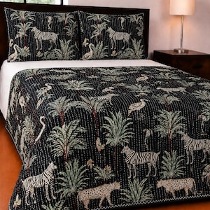 May include: A black quilt and two matching pillow shams featuring a repeating pattern of zebras, leopards, and cranes amidst palm trees and tropical foliage. The bedding set has visible white kantha-style stitching throughout the fabric.