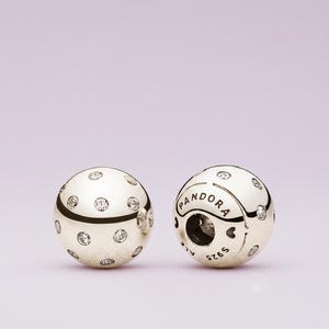 May include: Two silver Pandora charm beads. Each bead is spherical, with a polished finish and embedded clear crystals. One bead has the Pandora logo and S925 ALE markings.